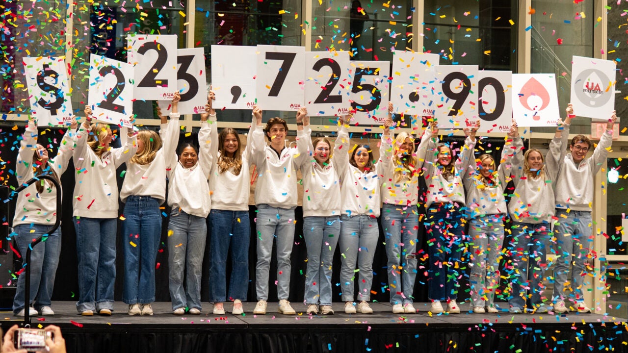 University students hold signs showing the total amount raised by UA Miracle